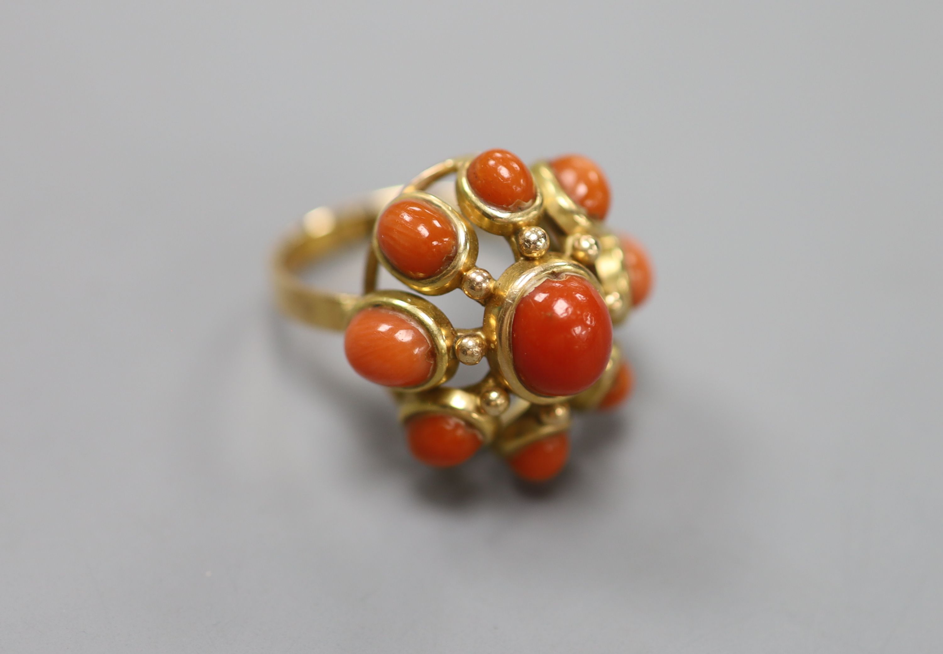 A yellow metal and nine stone coral bead cluster set dress ring, size O, gross 9.1 grams.